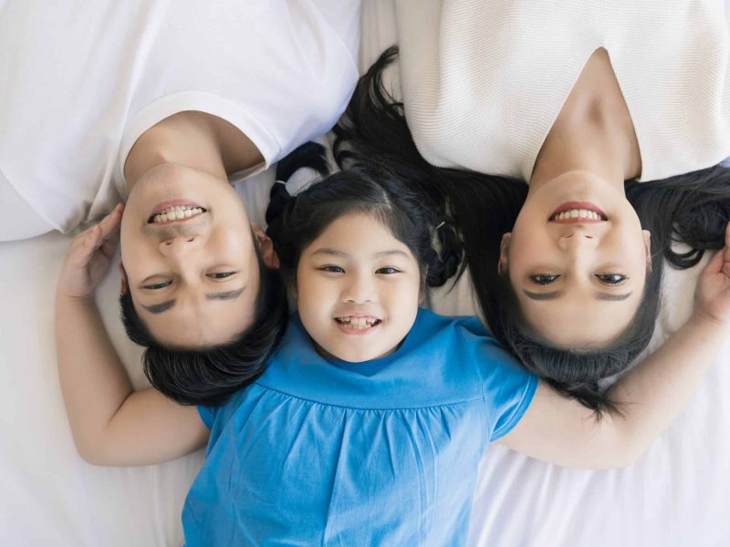 Happy Attractive Young asian Family Portrait Healthy harmony in life family day concept asian family man woman and little girl having good time together.top view bedroom mattress